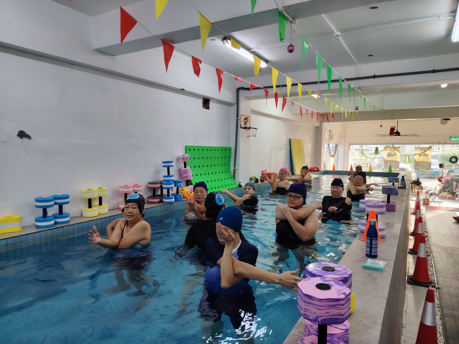 A class of adults and seniors stretching together during an Aqua Exercise session