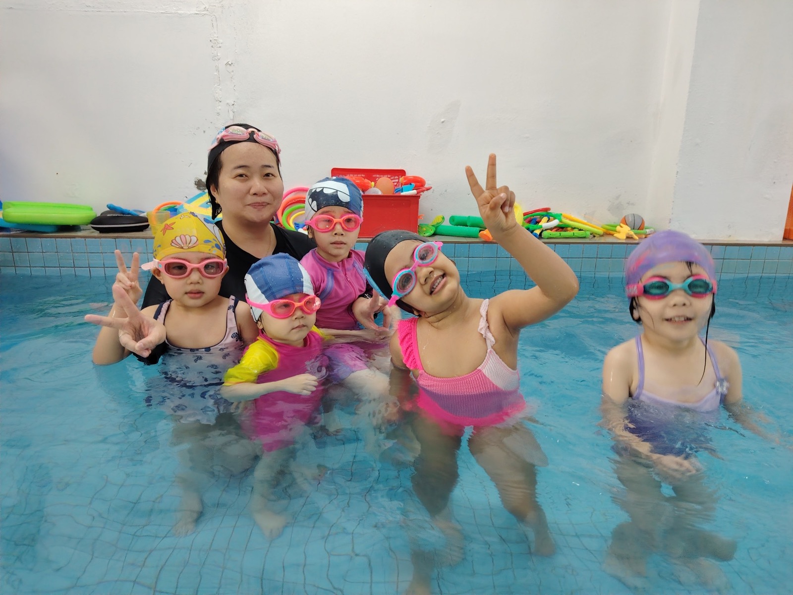 Children smiling together in the pool during a group class