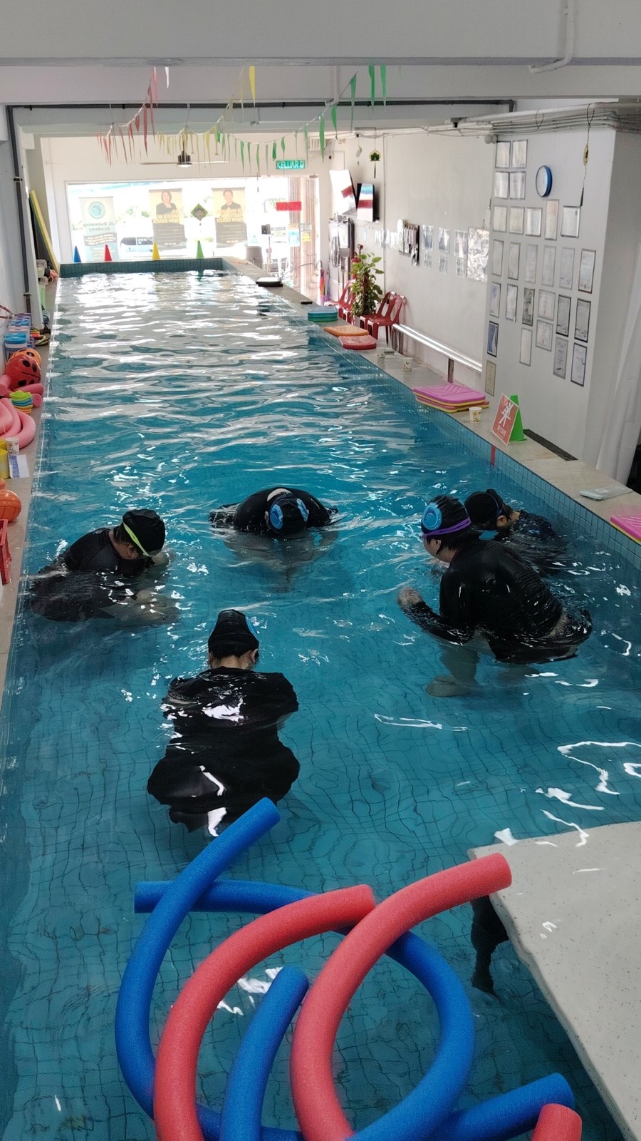 A family learning to swim side by side during a group class in the pool